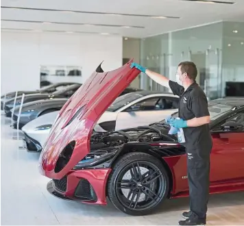  ??  ?? Downsizing: A worker, wearing a protective face mask, closes the bonnet of an Aston Martin DBS in a showroom at a Aston Martin Works dealership in Newport Pagnell, UK. The eliminatio­n of 500 positions equates to almost 20% of Aston Martin’s workforce. — Bloomberg