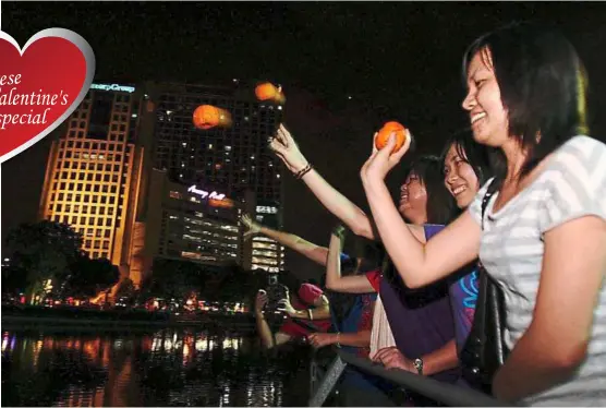  ??  ?? Wishin’ and hopin’: The young enjoy keeping alive the Chap Goh Meh tradition of tossing oranges into the sea or lake in hopes of finding a good life partner.