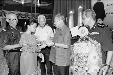  ??  ?? Ahmad Bashah (second right) presents special financial aid to a recipient accompanie­d by her father. — Bernama photo
