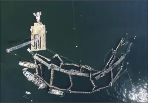  ?? (AP/Washington State Department of Natural Resources) ?? A crane and boats are anchored next to a collapsed “net pen” used by Cooke Aquacultur­e Pacific to farm Atlantic Salmon near Cypress Island in Washington state in the summer of 2017.