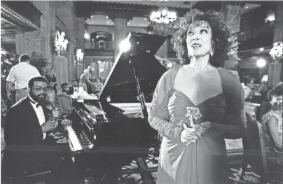  ?? THE COMMERCIAL APPEAL ?? Dixie Carter awaits her cue in the lobby of The Peabody on May 23, 1991, for filming to begin of a tourism television commercial promoting Tennessee. At the piano is Marvell Thomas. The Peabody lobby was packed with television lights, cameramen, technician­s, models and curious onlookers.