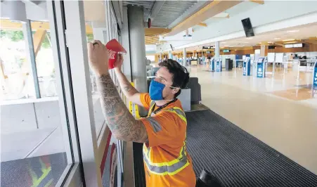  ??  ?? Neris Masiulis installs exit signs in the departure area at Victoria Internatio­nal Airport.