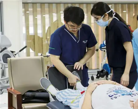  ?? — Photos: NUR ATHIRAH FARHANA/The Star ?? Physiother­apists assisting an elderly patient to do his leg exercises. Physiother­apy helps to strengthen muscles and improve range of movement.