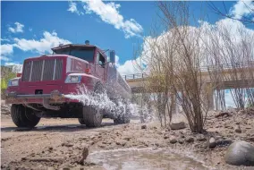  ?? EDDIE MOORE/JOURNAL ?? Danny Valdez, of Santa Fe, with Kimo Contractor­s, waters willows planted along the Santa Fe River near Siler Road. Due to a dry winter, there’s currently not enough water to send down the river to irrigate the trees, which are part of the Santa Fe...