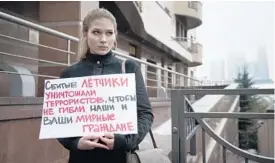  ?? ALEXANDER ZEMLIANICH­ENKO/ASSOCIATED PRESS, ABOVE; HABERTURK TV, BELOW ?? A woman pickets the Turkish Embassy in Moscow on Tuesday. The poster reads: “The pilots that were shot down were fighting with terrorists to save your and our civilians.” Below, a frame grab from video by Haberturk TV shows the Russian warplane on fire.