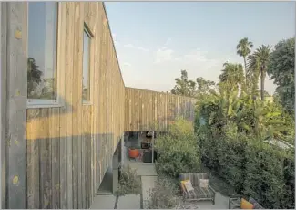  ??  ?? AT ONCE rustic and modern, the Venice duplex owned by Jenn McCabe and Lee Frees is sheathed in reclaimed, weathered wood. Under a sloped metal roof that looks a bit barnlike, the home transition­s from one story facing the street to two stories at the...