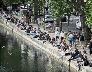  ?? — AFP ?? No levy: People sit on the bank of the Canal Saint-martin in Paris, as France eases lockdown measures taken to curb the spread of Covid-19. French Finance Minister Bruno Le Maire says he doesn’t want to reapply the country’s levy on wealth.