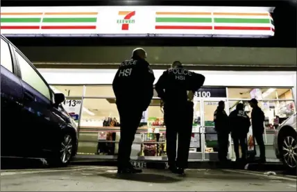  ?? CHRIS CARLSON, THE ASSOCIATED PRESS ?? U.S. Immigratio­n and Customs Enforcemen­t agents serve an employment audit notice at a 7-Eleven convenienc­e store Wednesday in Los Angeles. Agents said they targeted about 100 7-Eleven stores nationwide Wednesday.