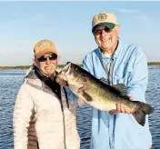  ?? STEVE WATERS Special to the Miami Herald ?? Capt. Steve Daniel, left, with a 7-pound Lake Okeechobee largemouth bass that he lifted into the boat for Glenn Sapir, who was visiting from Putnam Valley, New York.