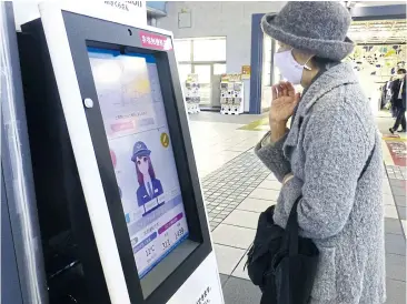  ??  ?? A rail passenger uses an AI-installed multilingu­al panel that acts as a guide at JR Shinagawa Station in Tokyo.
