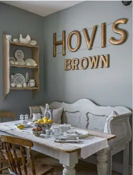  ??  ?? BELOW LEFT Gilded wooden Hovis Brown letters are a focal point in the kitchen. They were bought by Simon about 10 years ago from Norfolk Antique & Collectors Fair. The elm chairs and table once belonged to Simon’s mother. The Gustavian bench, dating from around 1890, is from Hungary and Catherine painted it in Autentico Chalk Grey. For similar benches try Country Home Antiques. BELOW RIGHT Catherine’s ever-growing collection of white antique ironstone makes an attractive display above the table in the corner of the kitchen.