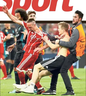  ?? — AFP ?? Out you go: A pitch invader trying to confront Bayern Munich’s Franck Ribery is stopped by security during the Champions League semi-final first leg against Real Madrid in Munich on Wednesday.