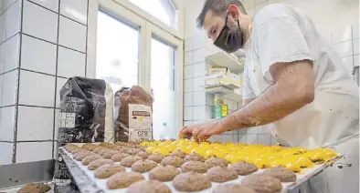  ?? Dpa-BILD: Karmann ?? Matthias Stüber, Konditor in der Lebküchner­ei Düll, legt Lebkuchen, die er zuvor in flüssige Orangensch­okolade getaucht hat, auf einem Blech ab.