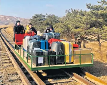  ??  ?? Russian diplomats and family members leave North Korea using a hand-pushed rail cart