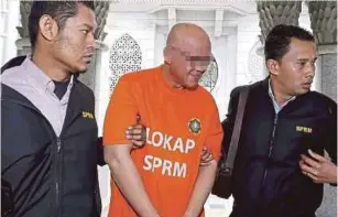  ?? PIC BY AHMAD IRHAM MOHD NOOR ?? The senior executive director of a property developmen­t firm being led to the magistrate’s court in Putrajaya yesterday.