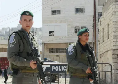  ?? NEWS SERVICE ?? Israeli border police officers stand guard Tuesday outside a building occupied by Jewish settlers in the West Bank city of Hebron. The settlers say they bought the property legally.
