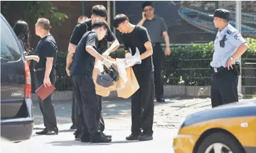  ?? — AFP photo ?? Security officials (centre, in black) work at the scene of a blast outside the US embassy in Beijing.