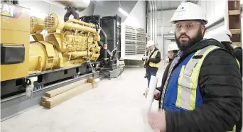  ??  ?? Jeff Hopkins devant la génératric­e qui fera fonctionne­r le centre en cas de panne d’électricit­é. - Acadie Nouvelle: Patrick Lacelle