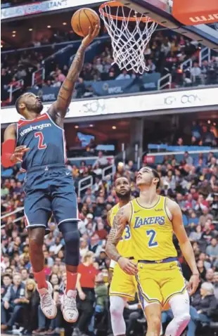  ?? AP ?? John Wall, de Washington, se eleva en busca de un canasto ante la mirada de LeBron James y Lonzo Ball, de los Lakers de Los Angeles en acción del partido de ayer en la NBA.