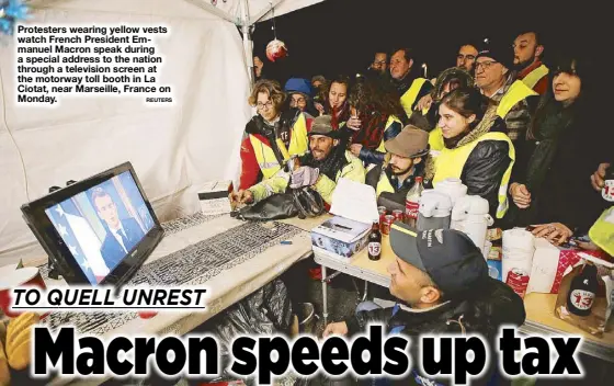  ?? REUTERS ?? Protesters wearing yellow vests watch French President Emmanuel Macron speak during a special address to the nation through a television screen at the motorway toll booth in La Ciotat, near Marseille, France on Monday.