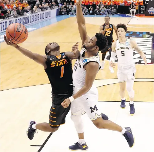  ?? JEFF ROBERSON / THE ASSOCIATED PRESS ?? Oklahoma State’s Jawun Evans is fouled on his way to the basket by Michigan Wolverines’ Derrick Walton Jr. in firstround action in the NCAA men’s basketball tournament in Indianapol­is. The Wolverines were 92-91 winners.