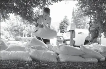  ?? JAKE BACON/ARIZONA DAILY SUN VIA AP ?? NOAH BESSLER, 16, STACKS SANDBAGS TO FORM A FLOOD BARRIER in front of a home in the Shadow Mountain neighborho­od of Flagstaff, downstream of a drainage from the Museum Fire on Wednesday. Forecaster­s warned of possible flooding in Flagstaff neighborho­ods with aging drainage systems below the wildfire.