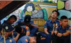  ?? NOEL CELIS/AFP/GETTY IMAGES ?? Exhausted police officers take a break from marshallin­g large crowds of activists outside government buildings in Manila on Monday.