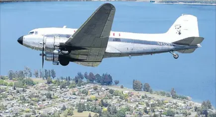  ?? Photo: BARRY HARCOURT 627338232 ?? Memorial flight: The DC3 Airscapade, featuring an image of Jean Batten on its tail, flies alongside a Southern Lakes helicopter over Te Anau on its way to the Te Anau-Manapouri airport.