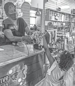  ?? NEAL RUBIN/DETROIT FREE PRESS ?? With an assist from customer service representa­tive Tyrand Goodwin, Yara Green selects a lanyard to hold her membership card for Chaney Library’s reading club. The 4-year-old from Detroit was making her first trip to a library.