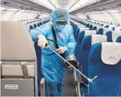  ?? VIETNAM AIRLINES ?? A worker wearing a protective suit disinfects a Vietnam Airlines plane this month.