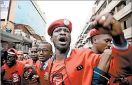  ?? ISAAC KASAMANI/GETTY-AFP ?? Robert Kyagulanyi, center, is joined by protesters in Kampala, Uganda, during a demonstrat­ion against a controvers­ial tax on the use of social media. Police fired live bullets and tear gas to disperse a rowdy crowd amid the protests.