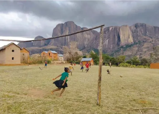  ??  ?? Ci-dessous : le massif du Tsaranoro attend l’orage menaçant, pendant qu’à ses pieds les enfants f inissent une partie de foot !