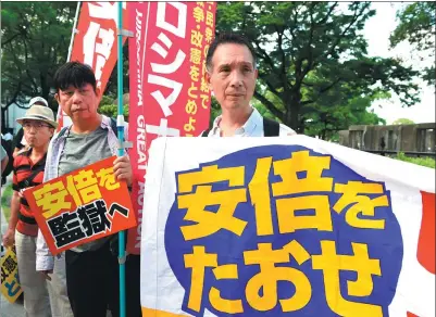  ?? MA PING / XINHUA ?? Protesters hold banners and shout slogans against Prime Minister Shinzo Abe in Hiroshima, Japan, on Sunday.
