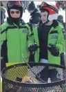  ?? DAVID JALA/CAPE BRETON POST ?? Nicolas Guy, left, and Matthew Chimone warm up beside the fire on the lodge-side deck at Ski Ben Eoin. The pair of ski racers was among the hundreds of people who took advantage of sunny skies to enjoy the last day of the local ski season.