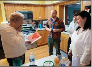  ?? (AP/Charles Rex Arbogast) ?? Deb Robertson (left) reacts to a card made for her by a student of her daughter Shannon Rodriguez (right) as her son Jake and niece Emma watch before a BBQ with family and friends at her Lombard, Ill., home on March 23.