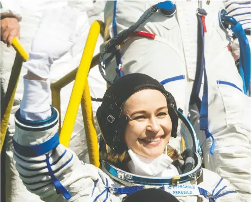  ?? ANDREY SHELEPIN / GCTC / ROSCOSMOS / HANDOUT VIA REUTERS ?? Russian actor Yulia Peresild waves farewell Tuesday as she boards the Soyuz MS-19 spacecraft for the launch at the
Baikonur Cosmodrome, Kazakhstan. She and film director Klim Shipenko plan to shoot the first movie in space.