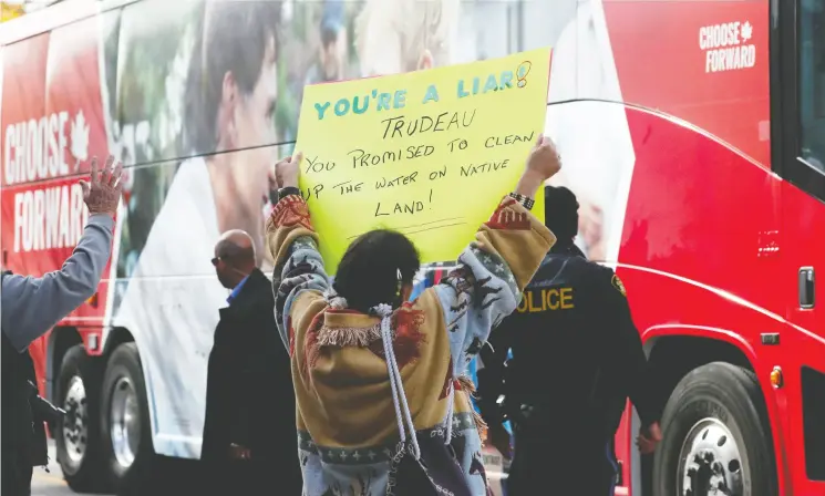  ?? Stephane Mahe / reuters ?? A demonstrat­or holds up a banner about clean water on First Nations reserves as Liberal Leader Justin Trudeau campaigns Friday in Orillia, Ont.