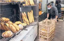  ?? MICHEL EULER/AP ?? Baker Ludovic Laurent pushes a basket of baguettes at Bigot bakery last week near Paris. The French are expressing worries over the price of the country’s iconic bread.