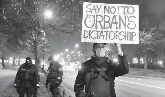  ?? CZAREK SOKOLOWSKI/AP ?? A man protests against Hungarian Prime Minister Viktor Orban during Orban’s November talks with Poland’s Prime Minister Mateusz Morawiecki in Warsaw, Poland. Some experts say COVID-19 has accelerate­d the curbing of individual freedoms and boosted the reach of the state. Hungary, for example, has banned children from learning about homosexual­ity.