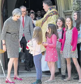  ??  ?? Prime Minister Theresa May and husband Philip chat to children outside her local church. In her Easter message she urged unity as the country prepares for Brexit