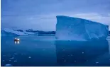  ?? ?? Un bateau navigue de nuit à proximité de grands icebergs dans l'est du Groenland.