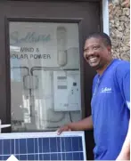  ??  ?? Sales Engineer standing outside a demo unit of a wind and solar hybrid system in Mombasa, Kenya