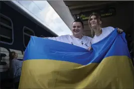  ?? FRANCISCO SECO — THE ASSOCIATED PRESS ?? Ukrainian rapper alyona alyona, left, and singer Jerry Heil hold the Ukrainian flag Thursday before departing from the main train station in Kyiv, Ukraine.