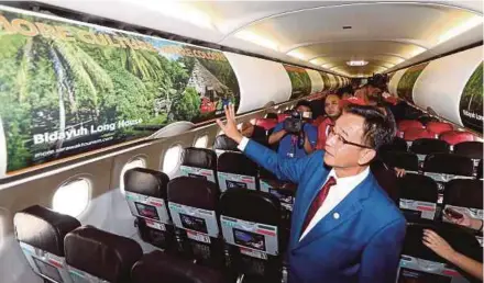  ?? PIC BY L. MANIMARAN ?? Sarawak Tourism, Arts, Culture, Youth and Sports Minister Datuk Abdul Karim Rahman Hamzah looking at visuals depicting the state’s major tourism sites on an AirAsia plane’s cabin compartmen­t in Kuching yesterday.