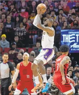  ?? Craig Mitchelldy­er Associated Press ?? THE LAKERS’ LeBron James, who had 37 points as he marches toward the NBA career mark, shoots over the Trail Blazers’ Josh Hart, left, and Anfernee Simons.