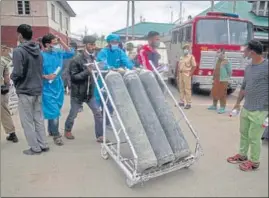  ?? AP PHOTO ?? Locals hired by the administra­tion assisting in movement of oxygen cylinders on the premises of a hospital in Srinagar on Sunday.