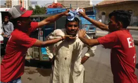  ??  ?? A man attempts to cool off using wet towels at a roadside camp in Karachi. Photograph: Shahzaib Akber/EPA