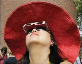  ?? ASSOCIATED PRESS ?? Ann Kim Tenhor, of Arlington, Mass., uses protective eclipse glasses to view a partial solar eclipse, Monday on the campus of Massachuse­tts Institute of Technology, in Cambridge, Mass.