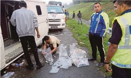  ?? PIC BY ZAIREE MOHD YASAK ?? Rescue personnel collecting the coins strewn on the North-South Expressway in Alor Gajah yesterday.