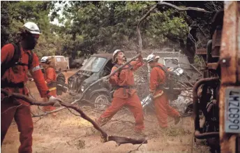  ??  ?? Firefighte­rs clear brush to create a break Monday while battling the Ferguson Fire in Mariposa County, Calif.